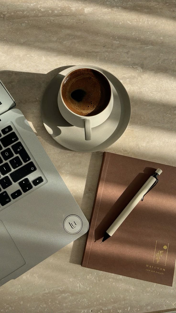 Portátil, café y cuaderno sobre una mesa de piedra con luz cálida